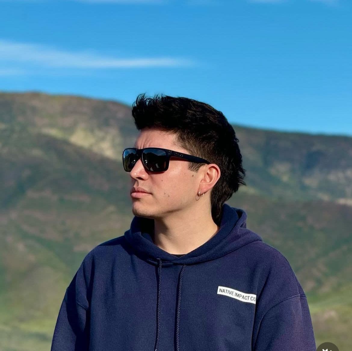 Benjamín Peña Díaz, de perfil y con lentes de sol, frente a un cerro. Fotografía en blanco y negro.